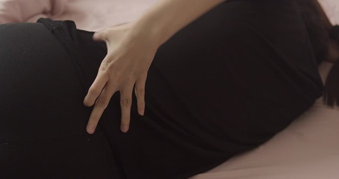 Unhappy Asain Woman injury and suffering on her back pain while sitting on her bed. close up shot.Using hand massage on painful spot.healthcare and medical concept.