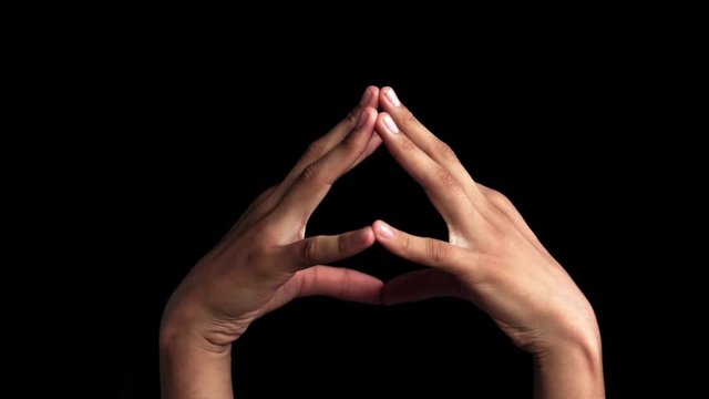 Pair of human hands coming up and showing demonstrating Hakini Yoga Mudra Hand Gesture isolated on black background.