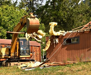 Excavator pulling insulation off house demo