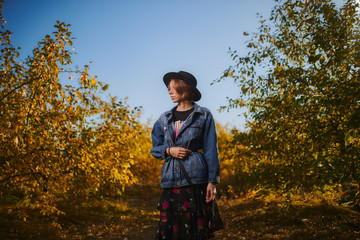 A young girl walks through the autumn forest with yellow leaves