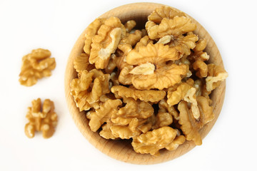 Drewniana miska wypełniona orzechami włoskimi na białym tle