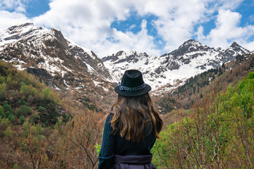 A girl in nature watching the snow cap mountains in the Alps 