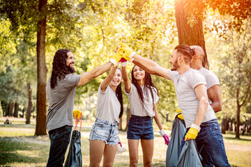Team of friends cleaning up the park by collecting litter into plastic bags