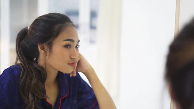 Pretty teenage girl looking at herself through the mirror in the bedroom at home. Shot in 4k resolution