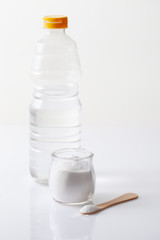 A jar of baking soda and a bottle of vinegar on a white table