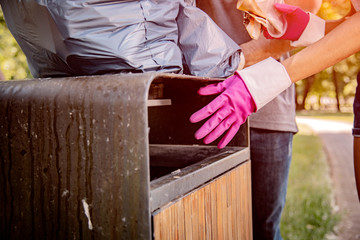 Group of friends throwing collected in the park litter into the trash can.