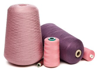 Cones and spools of pink and violet sewing threads isolated on white background