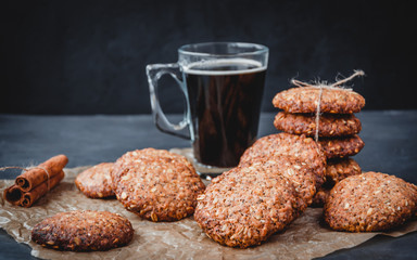 Homemade healthy oat cookies with cinnamon and glass mug of coffee on brown parchment. Healthy food concept. Healthy snack. Copy space