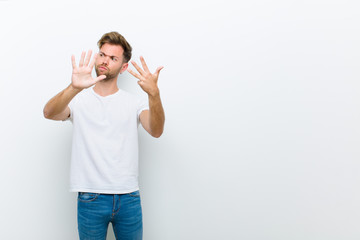 young man smiling and looking friendly, showing number nine or ninth with hand forward, counting...