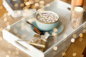 holidays and still life concept - hot chocolate with marshmallow, christmas gift and candles on table