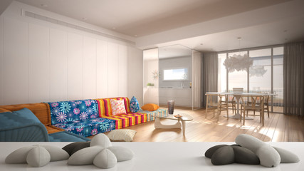 White table, desk or shelf with five soft white pillows in the shape of stars or flowers, over blurred modern colorful living room, minimalist architecture interior design concept