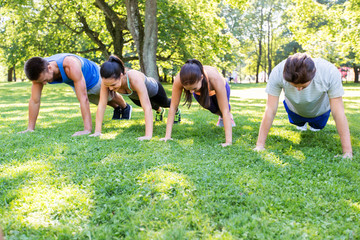 fitness, sport and healthy lifestyle concept - group of people doing push-ups or plank exercise at...