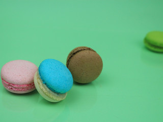 Colorful french macarons (macaroons) cake,  delicious sweet dessert on green background with copyspace, food background concept.