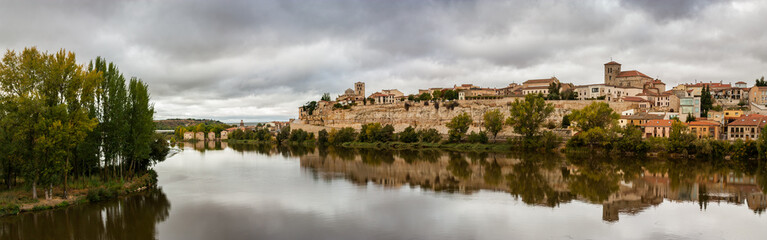 Fototapeta na wymiar Panorama view of the reflection of the cityscape on the rocky cliff shore of the Douro River of Zamora, Spain.