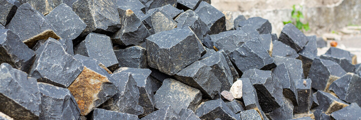 Banner for a site selling building materials with a pile of stones. Stones for masonry pavement and sidewalk. Building granite dark cobblestones.
