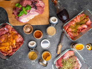 Raw meat in different marinades as soy sauce, pomegranate sauce, spices and herbs in a glass bowls