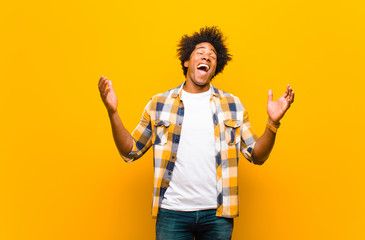 young black man looking extremely happy and surprised, celebrating success, shouting and jumping...