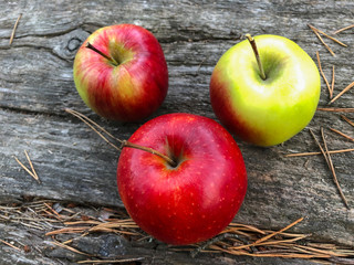 Three juicy apples on a wooden background.