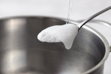 Foaming baking soda slaked with vinegar in a spoon over a metal dish