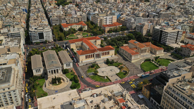 Aerial photo of famous trilogy landmark buildings of Academy of Athens, Panepistimio or University, public Library with iconic Lycabettus hill at the background, Athens, Attica, Greece