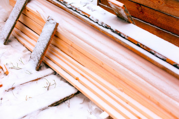 Stack of lumber covering in snow outdoors.