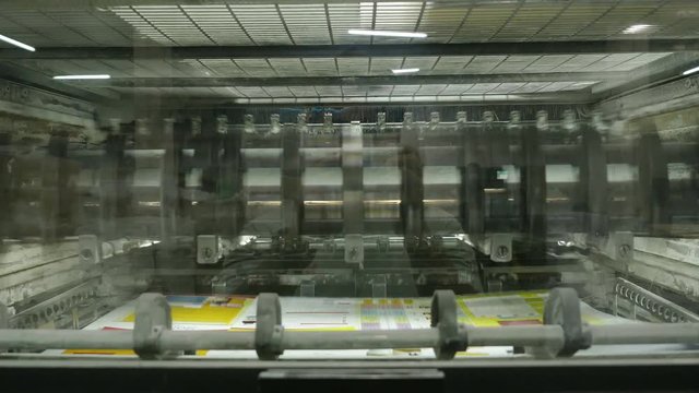 Old vintage printing press is working draws paper in printing factory.