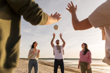 volleyball, leisure games and people concept - happy friends playing with ball on beach in summer