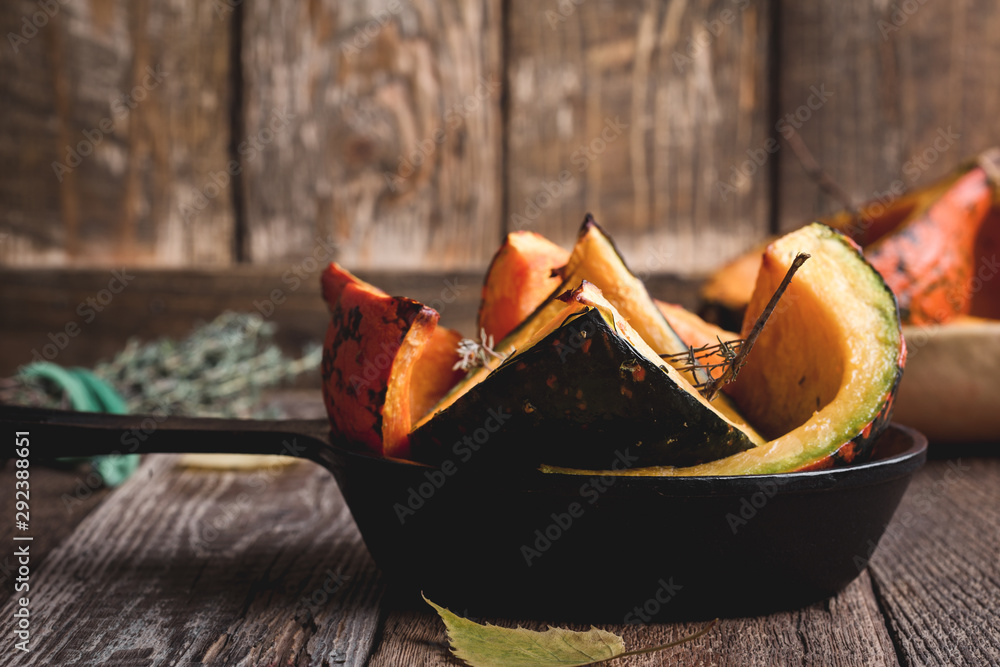 Wall mural Baked pumpkins with thyme in cast iron skillet