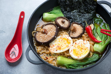 Ramen with pak-choi, shiitake, nori and egg in a cast-iron pan, close-up, studio shot