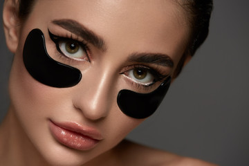 Beauty Woman with Eye Patches. Female With Natural Makeup And Black Collagen Patches On Fresh Facial Skin. Eye Skin Treatment