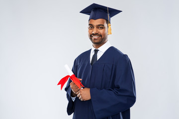 education, graduation and people concept - happy smiling indian male graduate student in mortar...