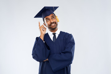 education, graduation and idea concept - happy smiling indian male graduate student in mortar board...