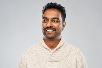 emotion, expression and people concept - smiling indian man in knitted woollen sweater over gray background
