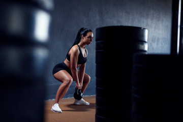 Sport active woman make training on gym with weights - squat with kettlebell. Sexy athletic girl, with black hair.