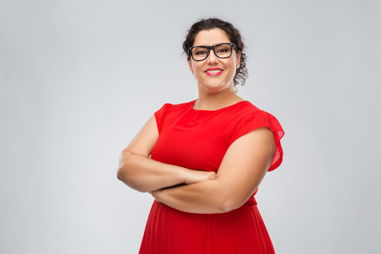 vision, education and eyesight concept - happy woman in red dress and glasses with crossed arms over grey background