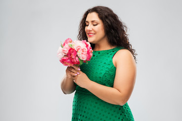 people and portrait concept - happy woman in green dress with flower bunch over grey background