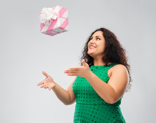 holidays, presents and people concept - happy woman in green dress playing with gift box over grey background