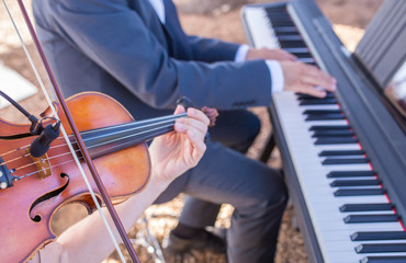 Violin and piano musical duo performing during outdoor party