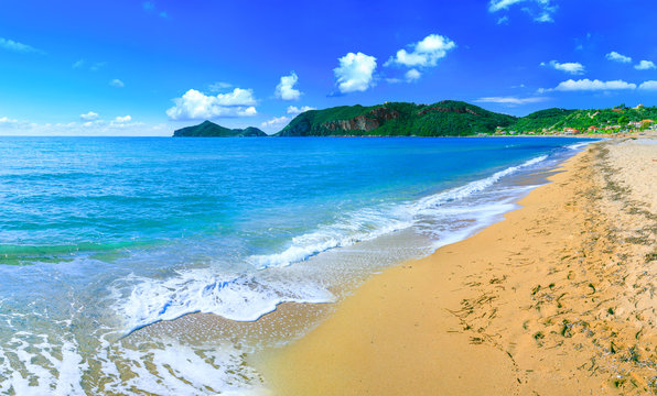 Beautiful summertime panoramic seascape. Awesome view picturesque green slopes coastline sea with crystal clear azure water. Big golden sand beach.