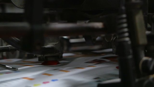 Old vintage printing press is working draws paper in printing factory.