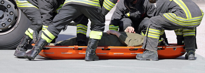 firefighters put a wounded person on a stretcher