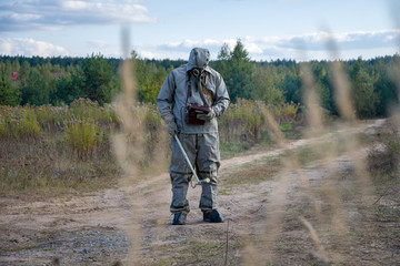 Military dosimetrist measures the radiation of the surrounding nature, chemical protective suit and gas mask, Sunny day