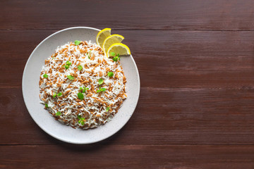 Turkish rice pilaf with orzo in a plate on a brown wooden background. Top view, copy space. 