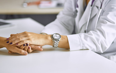 Woman doctor calms patient and holds hand