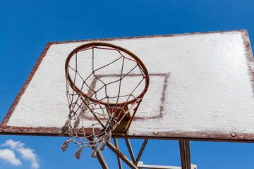 old and vintage basketball backboard and blue sky with clouds as a background