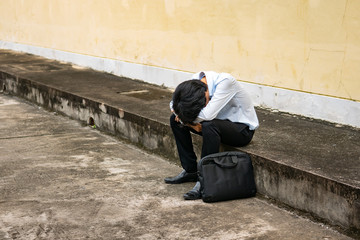 a man in formal outfit sitting hopeless on footpath