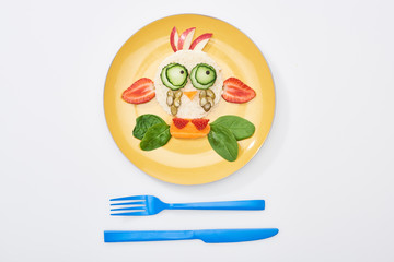 top view of plate with fancy cow made of food for childrens breakfast near cutlery on white background
