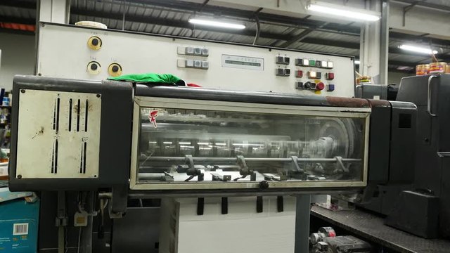 Old vintage printing press is working draws paper in printing factory.