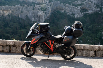 A motorcycle parked with luggage and helmet in front of a beautiful landscape