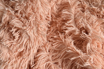 Pink sheepskin rug background. Fabric made of faux fur with long nap used for clothing and furniture and bedspreads. Detail of soft hairy skin material. Abstract Pink wool , fabric background.